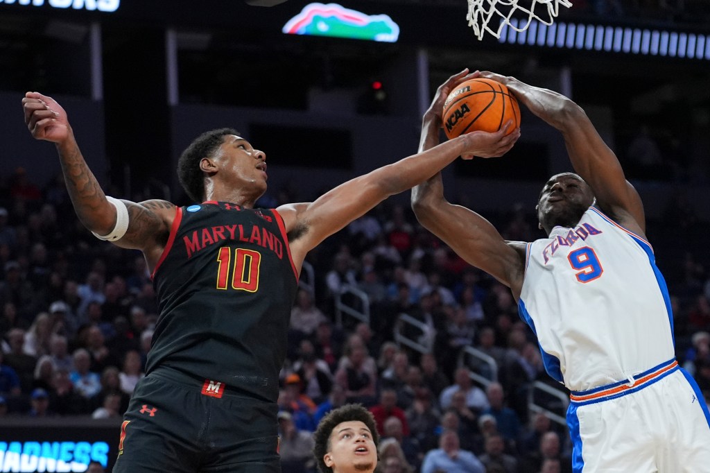 Maryland forward Julian Reese and Florida center Rueben Chinyelu reaching for a basketball during the NCAA tournament game, both wearing their respective team jerseys.