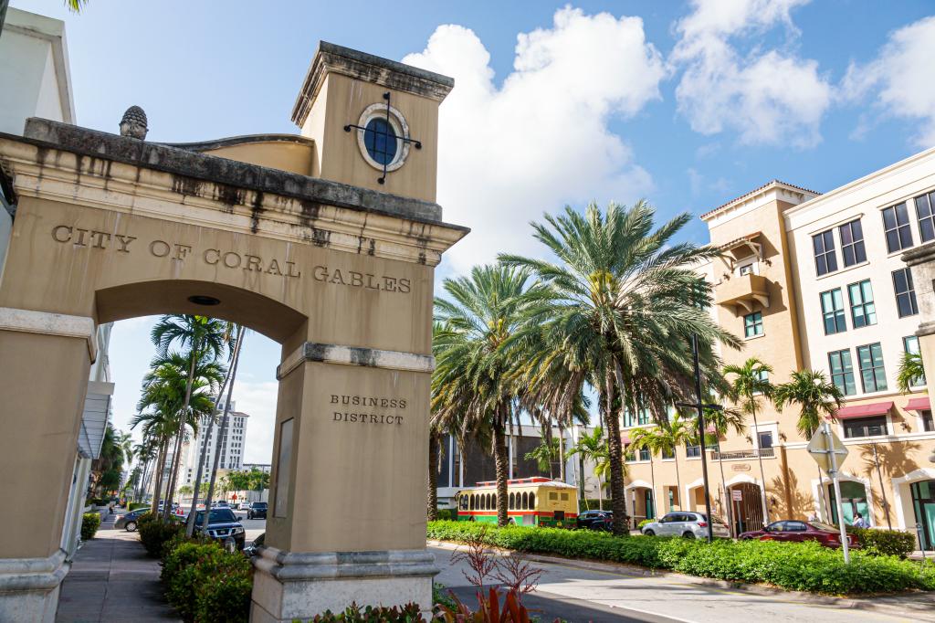 Stone archway with palm trees and cars on Ponce de Leon Boulevard in Miami Beach, Florida.