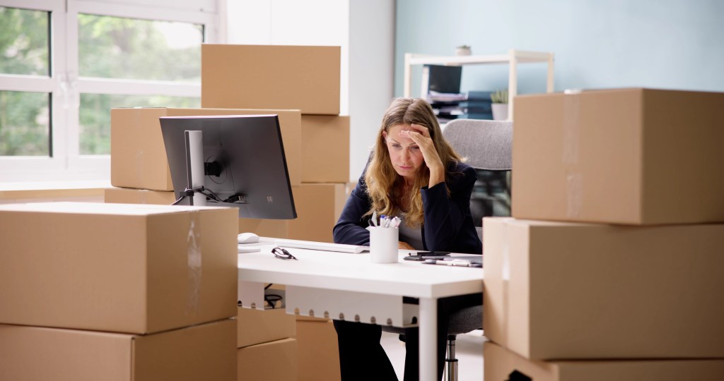 Stressed Entrepreneur working from home office with boxes around her 