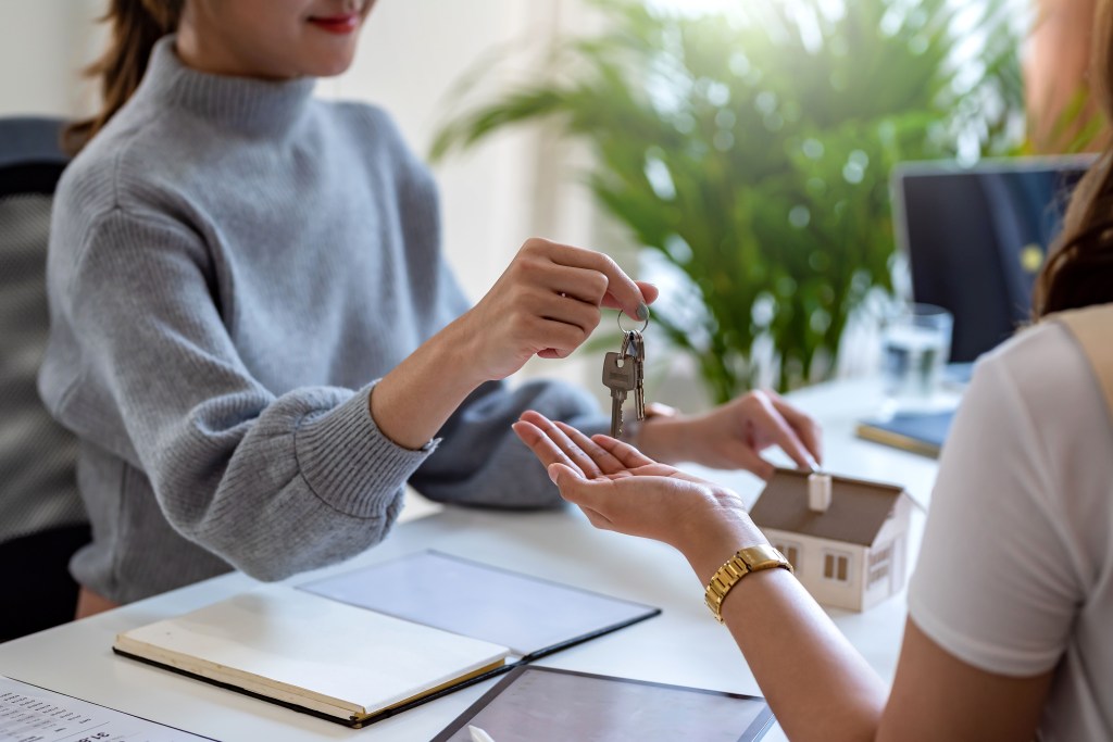 Real estate agent giving keys to house woman owner.