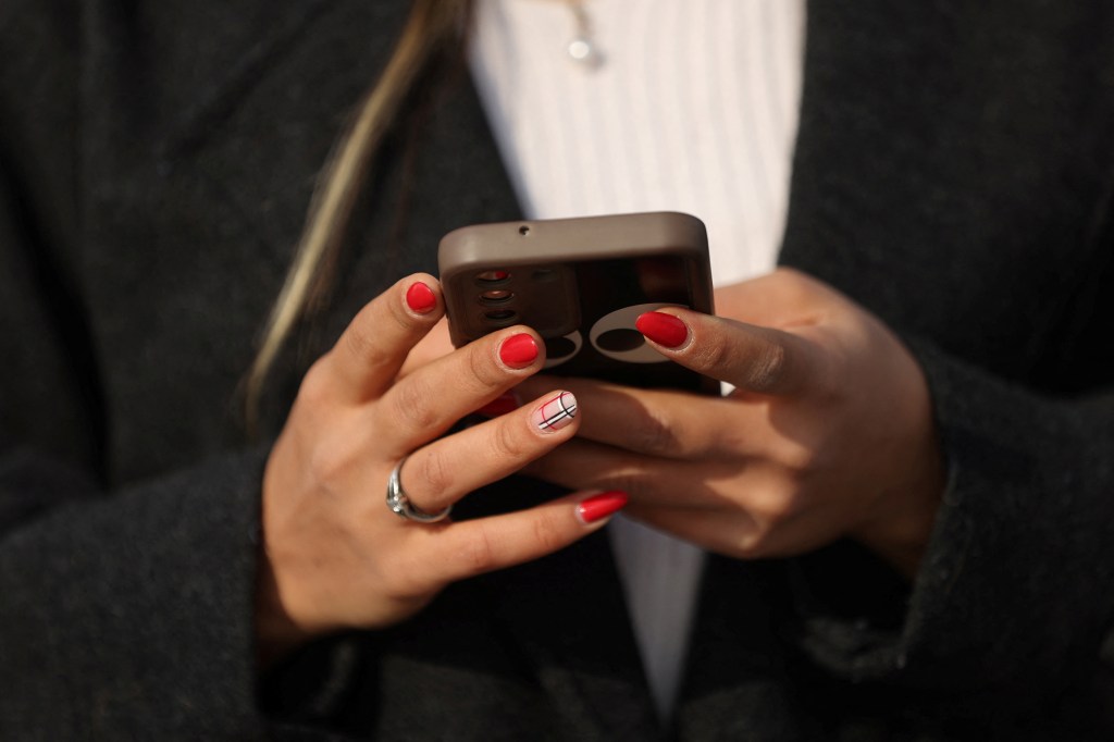 Iranian woman looking at her mobile phone in Tehran, Iran, after the lift of WhatsApp and Google Play ban
