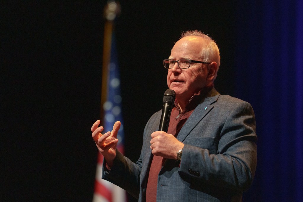 Minnesota Governor Tim Walz holding a microphone during a town hall in Eau Claire, Wisconsin