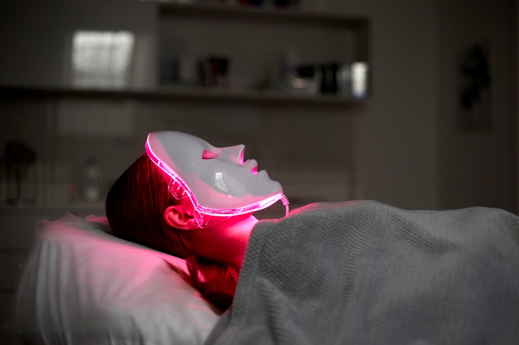 Cosmetic face mask with red light. the girl is wearing a mask. Health and beauty.