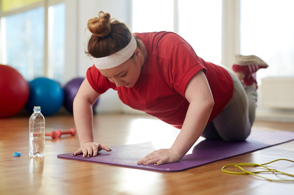 Modifications, like knee push-ups, reduce strain on the body and allow beginners to focus on proper form.  Here, a young woman does a modified knee push-up.