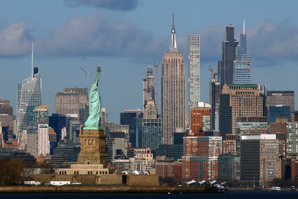 The Statue of Liberty stands in front of the Empire State Building and other buildings across the skyline of midtown Manhattan in New York City on February 1, 2025, as seen from Bayonne, New Jersey.