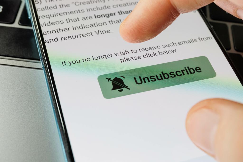 A finger touching the unsubscribe button on a smartphone screen