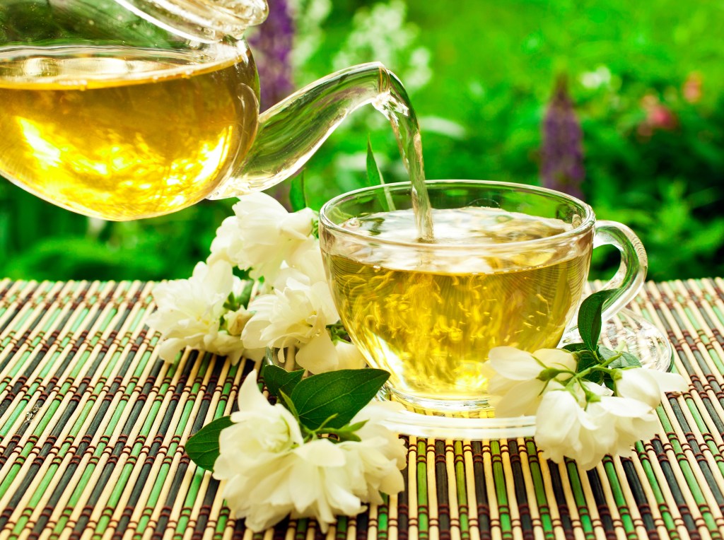Ash calls green tea "one of the most underlooked factors in longevity — it's easy, and it's cheap, and you can do it every day." Green tea is poured into a glass mug here.