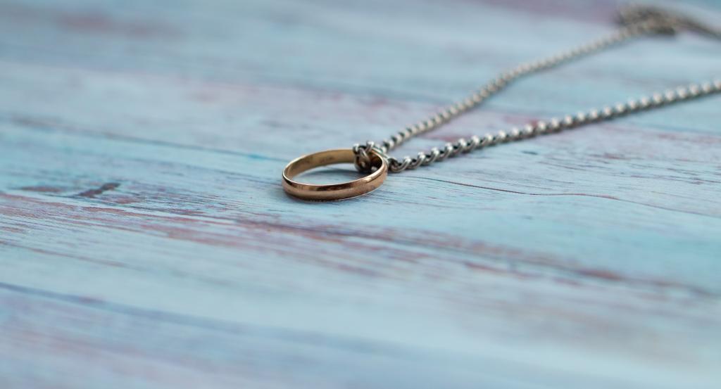 Silver chain and gold ring displayed on a wooden background