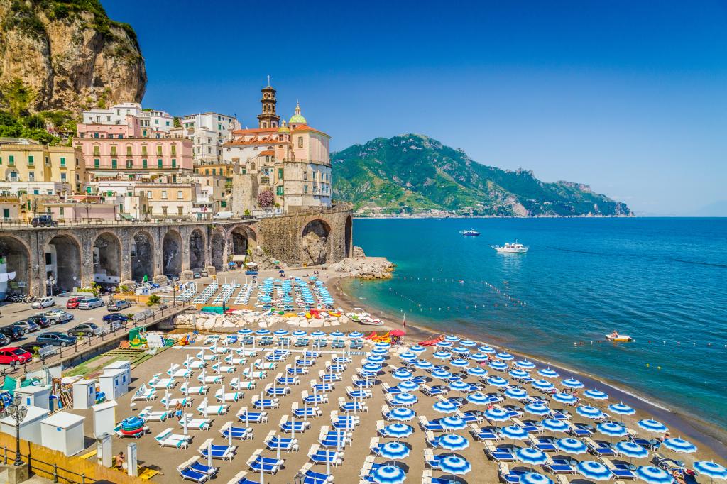Atrani town on the Amalfi Coast in Italy, featuring a beach with chairs and umbrellas and a building on the side