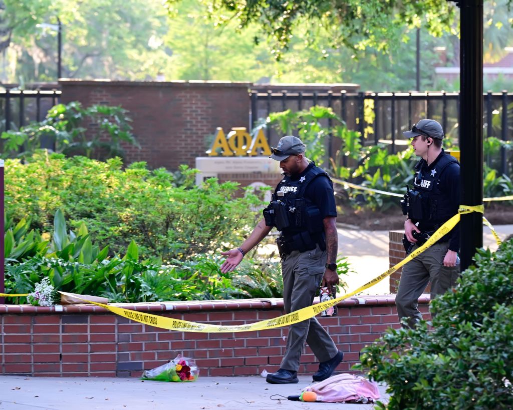Officials investigate the shooting behind police tape set up to preserve the crime scene.
