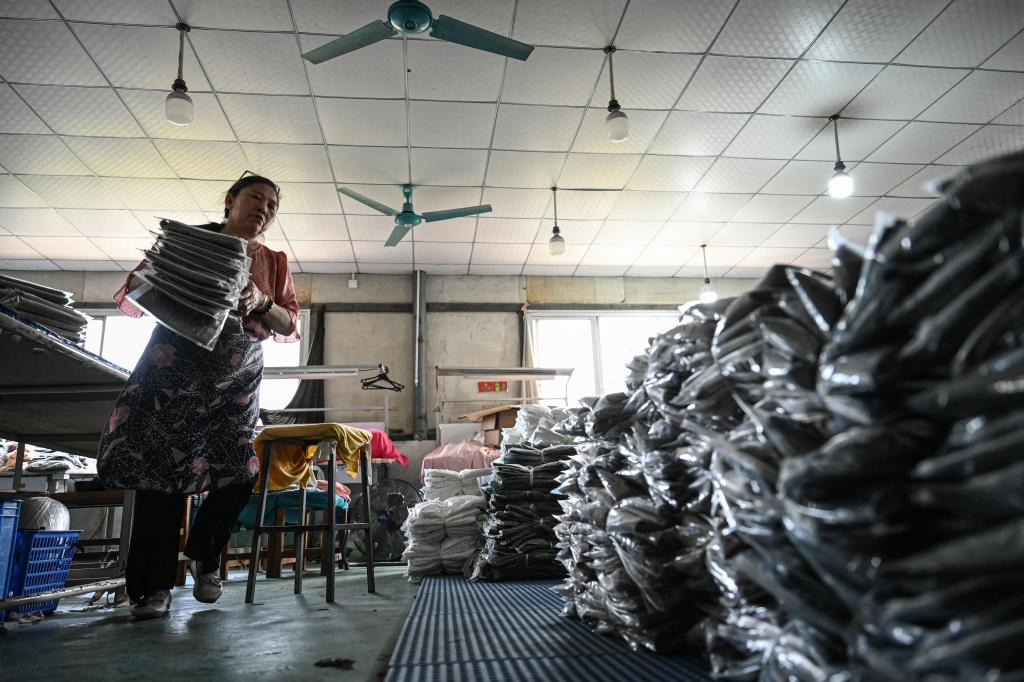 An employee sorts out garments for the online Chinese e-commerce company Temu at a clothing factory in Guangzhou, in southern China's Guangdong province on April 16, 2025. 