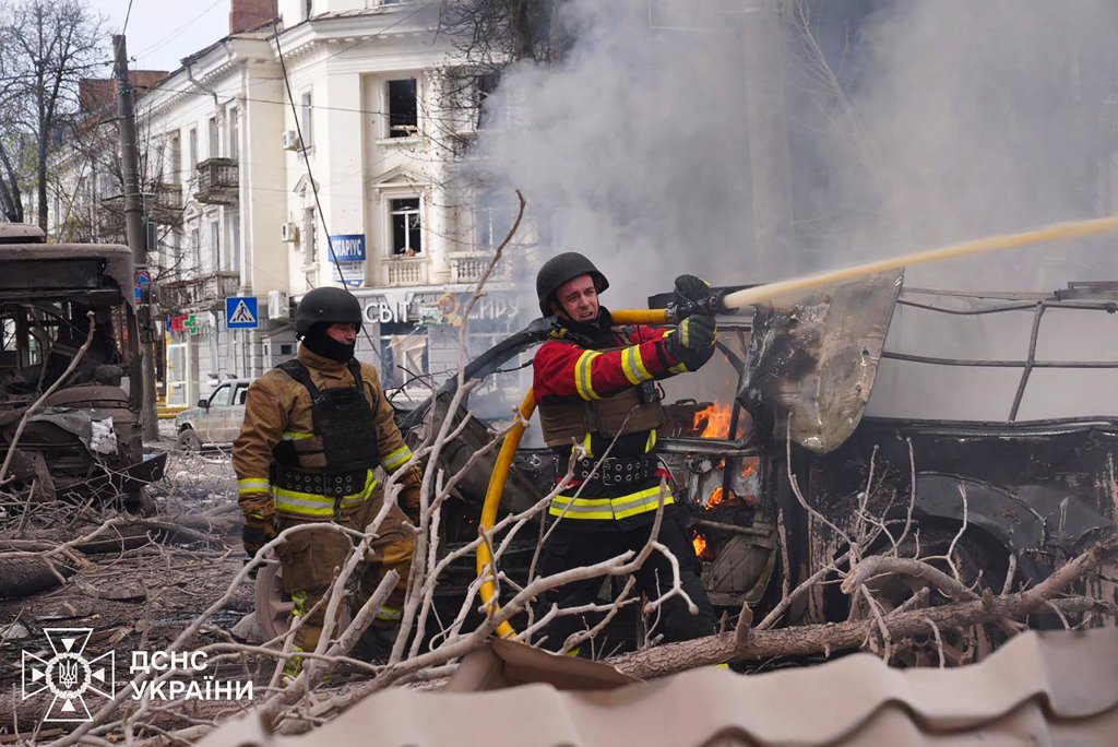 Ukrainian rescuers working at a missile attack site in Sumy, extinguishing a fire on a burning truck, after a Russian strike