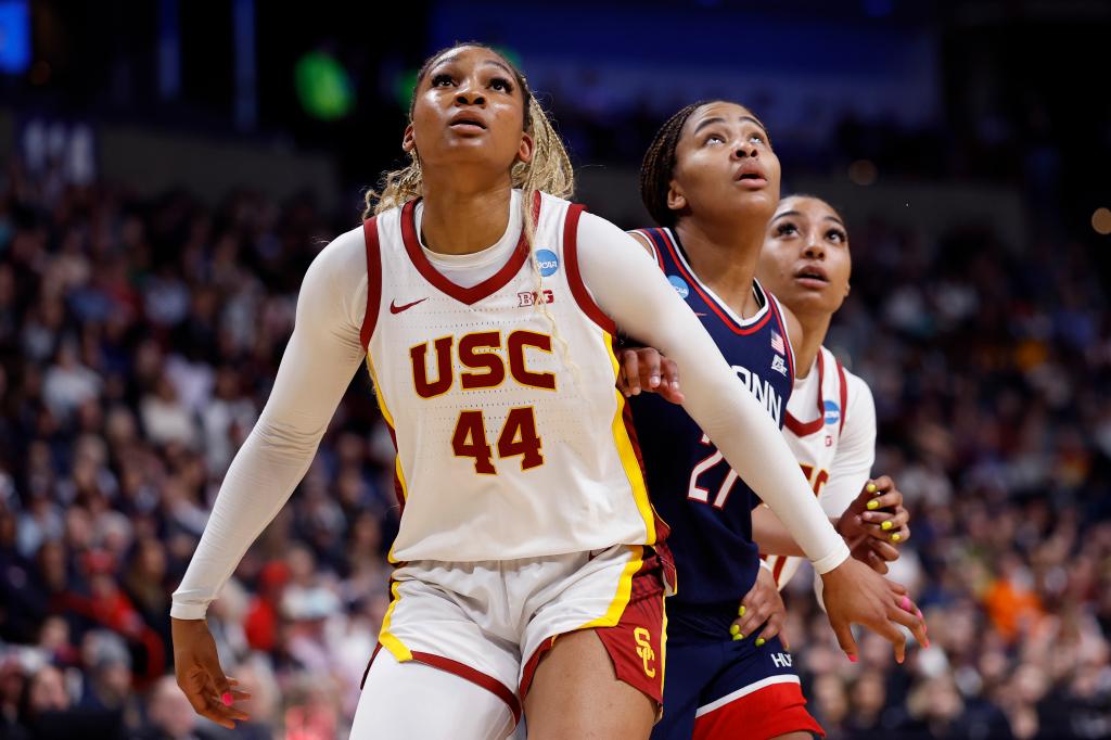 Kiki Iriafen of the USC Trojans blocking Sarah Strong of the UConn Huskies during a women's basketball game in the Elite Eight round of the NCAA Tournament