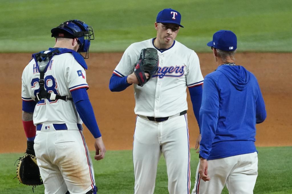 Texas Rangers starting pitcher Patrick Corbin (46) is visited on the mound by catcher Jonah Heim (28) and pitching coach Mike Maddux (31) during the fifth inning against the Los Angeles Angels.