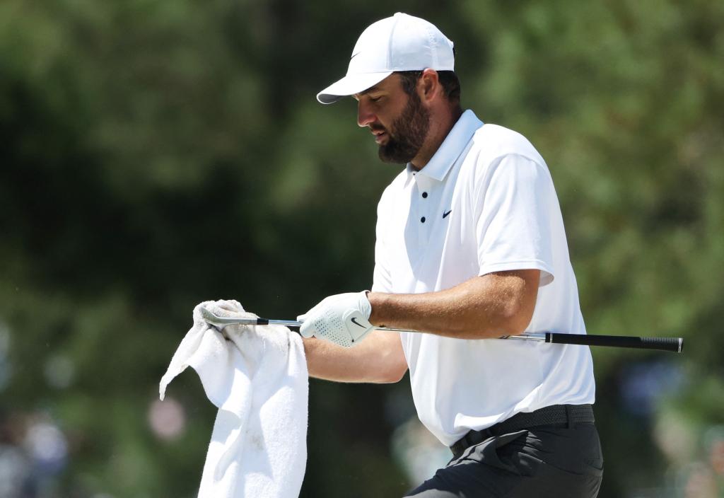 Scottie Scheffler wipes off the grooves on one of his clubs during his Masters practice round.