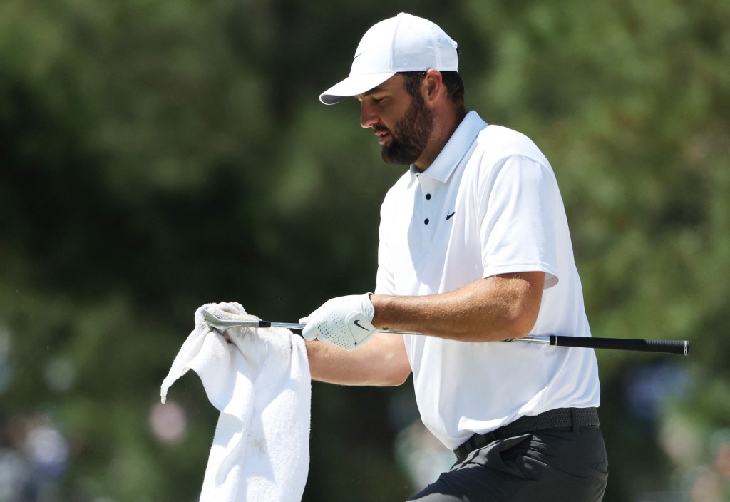 Scottie Scheffler wipes off the grooves on one of his clubs during his Masters practice round.