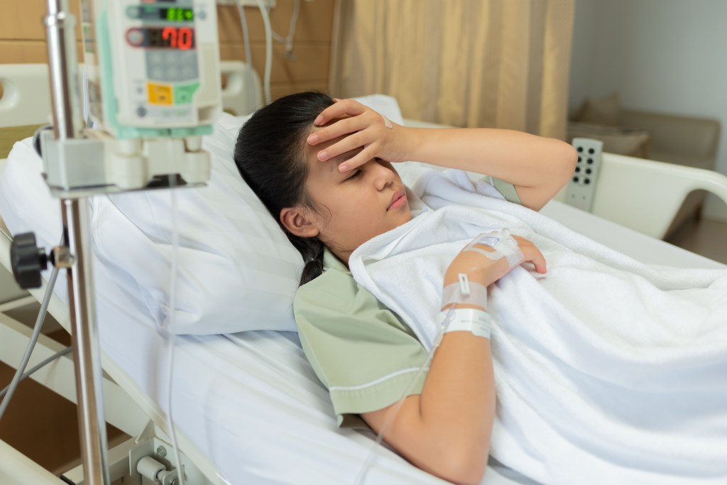 A young woman lies in a hospital bed with a headache after ingesting a THC product. 