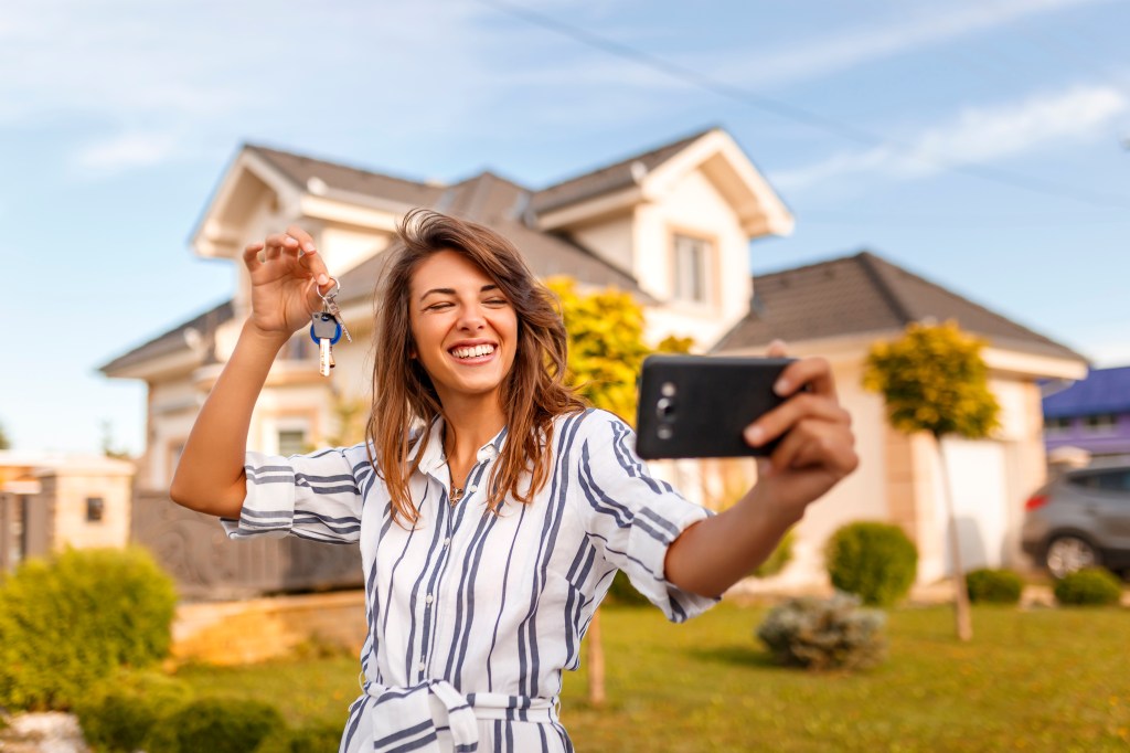 young woman standing in front of her new house