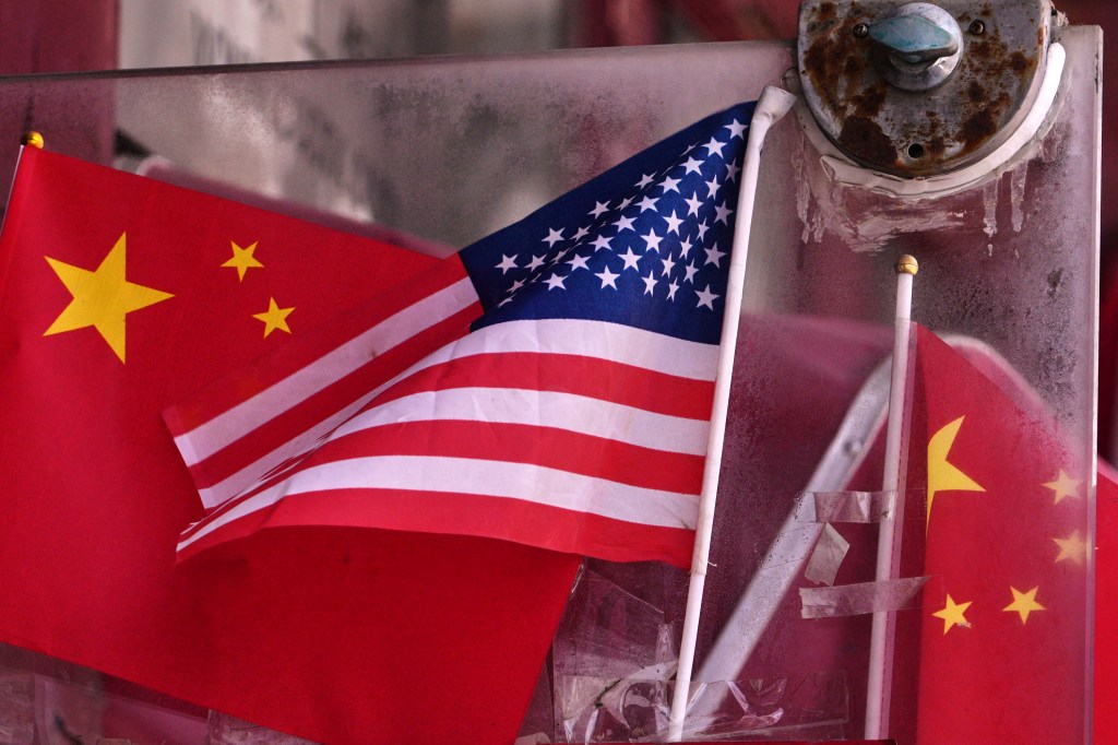 China and U.S. national flags are seen on display on an entrance door of a souvenir shop in Beijing on April 3, 2025. 