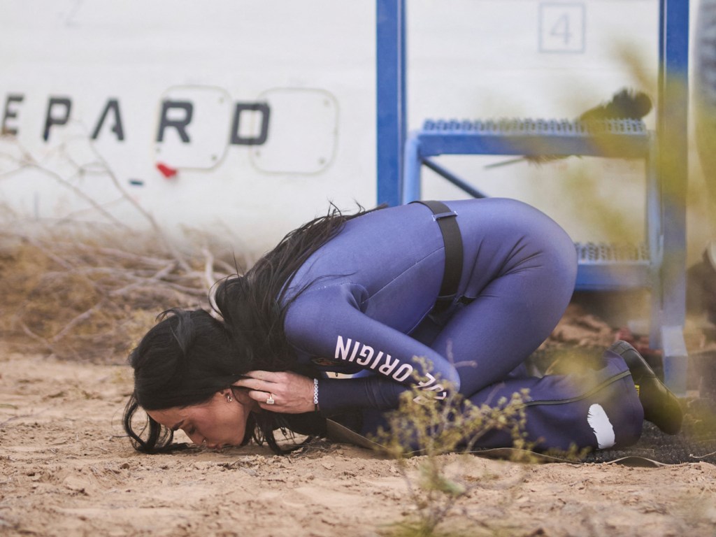 Katy Perry in a spacesuit, kissing the ground after returning from her Blue Origin spaceflight