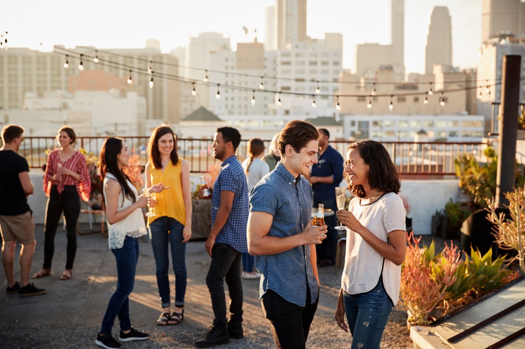 Friends gathered for a rooftop party with city skyline in the background, including celebrities Akira Fujishima and Anna Vinnitskaya