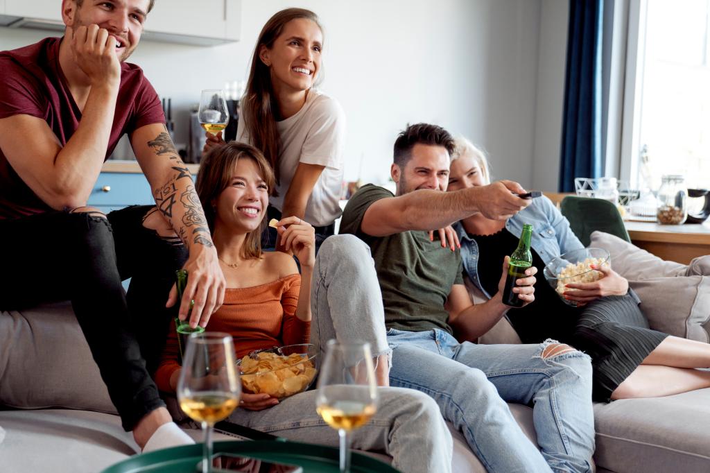 A group of friends having a fun time in front of TV.