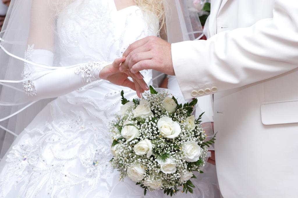 Groom delicately placing a wedding ring on the bride's finger