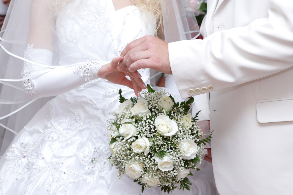 Groom delicately placing a wedding ring on the bride's finger