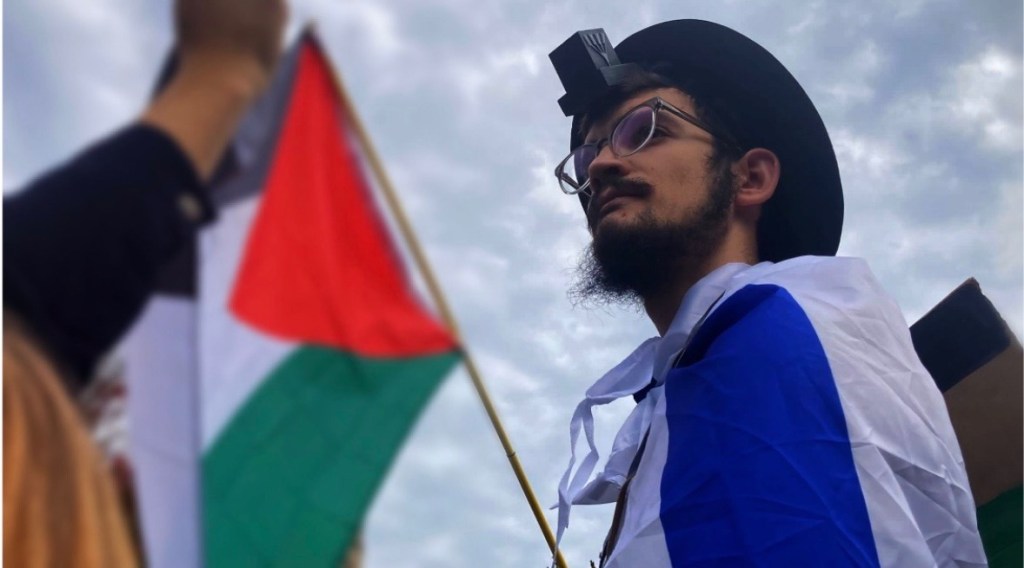 Netanel Crispe with a Palestinian flag in the foreground.