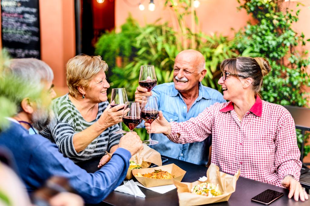 Happy friends toasting red wine during a dinner party. 