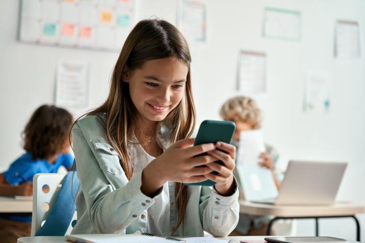 Happy latin hispanic kid girl school student using smartphone