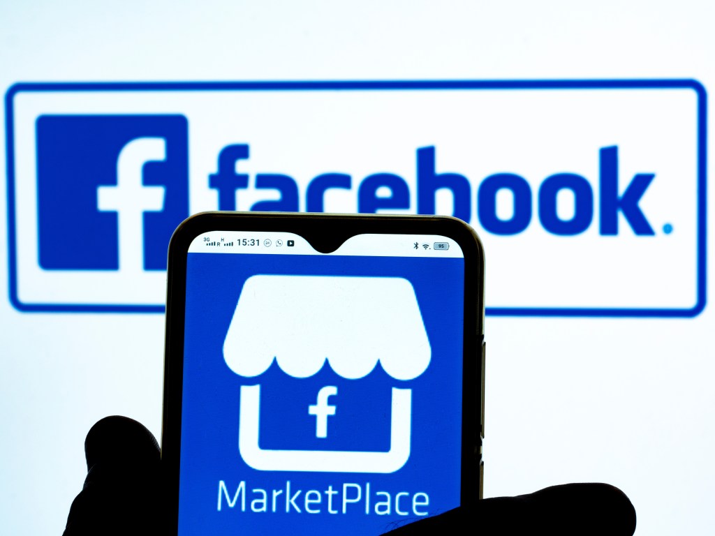 Marketplace by Facebook icon is seen displayed on a smartphone screen with the Facebook logo in the background.