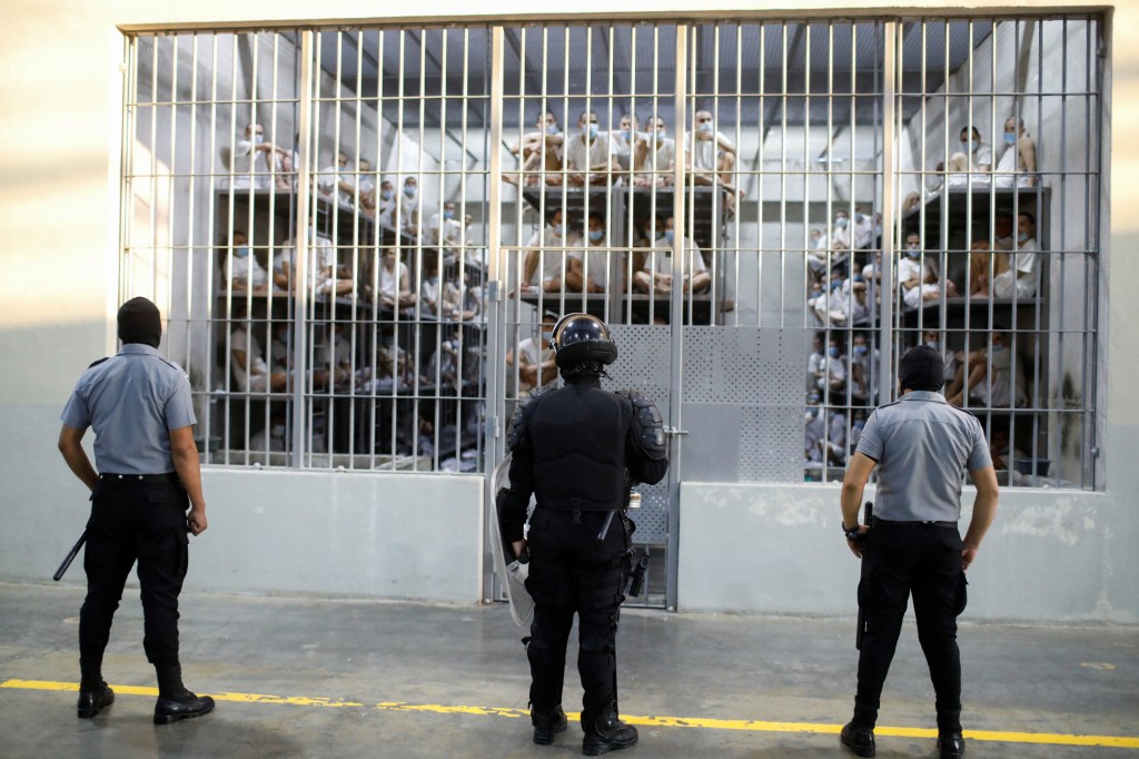 Policemen standing guard near a prison cell during a media tour at CECOT prison in Tecoluca, El Salvador