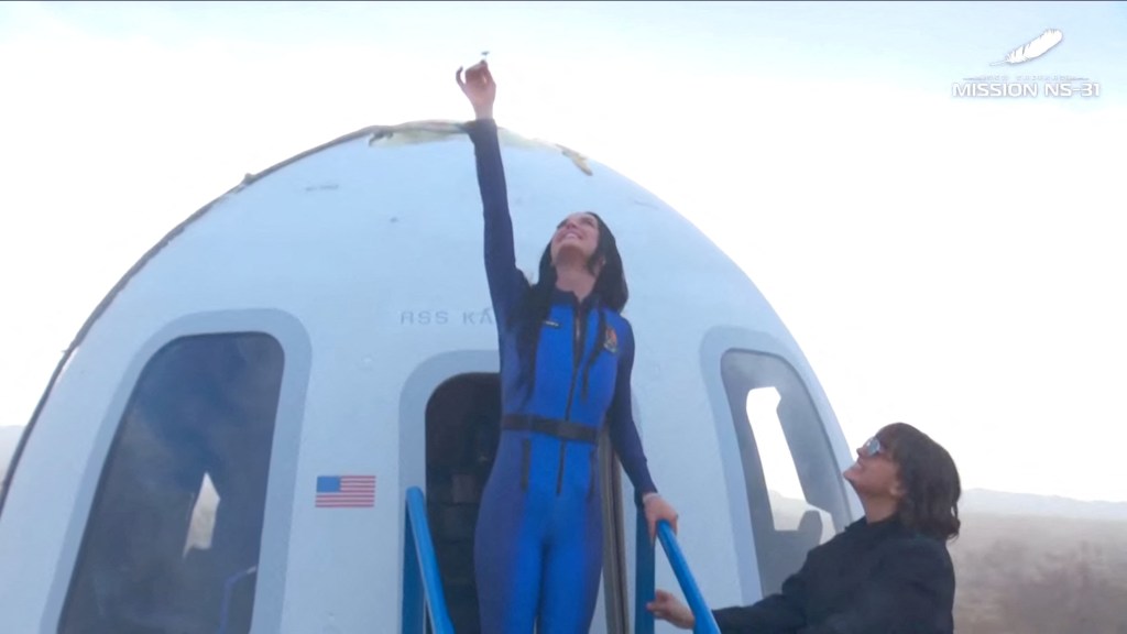 Katy Perry in a blue jumpsuit exiting a Blue Origin spacecraft after an all-female space mission