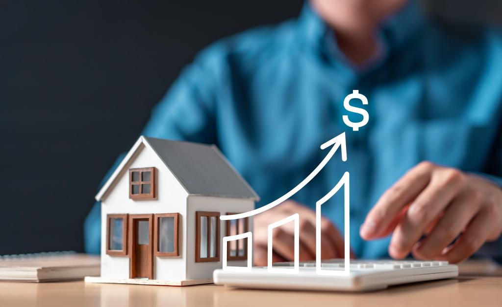 A person is typing on a keyboard in front of a house with a dollar sign on it and a chart.