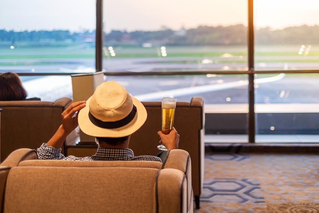 Having a beer or two at the airport may leave you dehydrated with an urgent need to use the restroom. Here, a man drinks a beer at the airport.