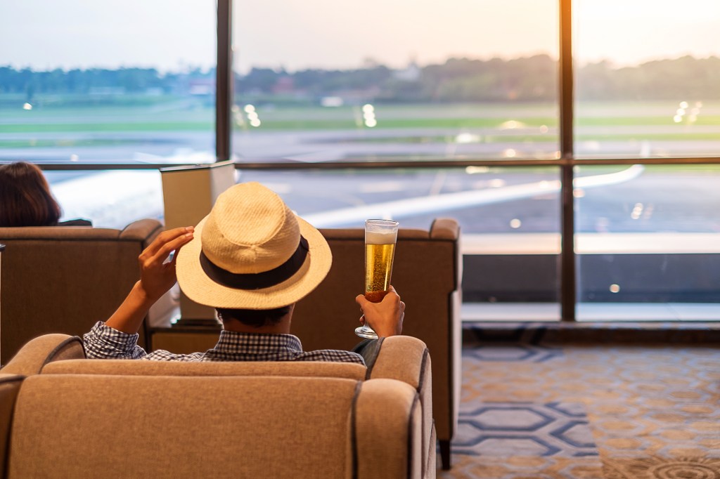 Having a beer or two at the airport may leave you dehydrated with an urgent need to use the restroom. Here, a man drinks a beer at the airport.