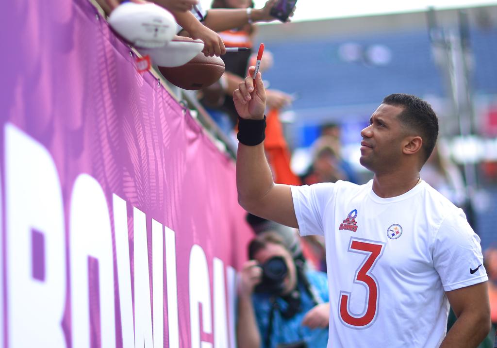 Russell Wilson of the Pittsburgh Steelers in a white jersey, signing autographs with a red marker at the NFL Pro Bowl Games in Orlando, Florida.