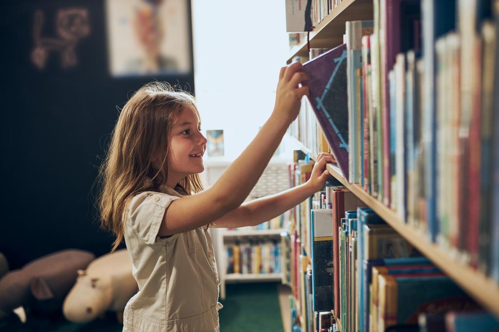 Schoolgirl choosing book in school library.