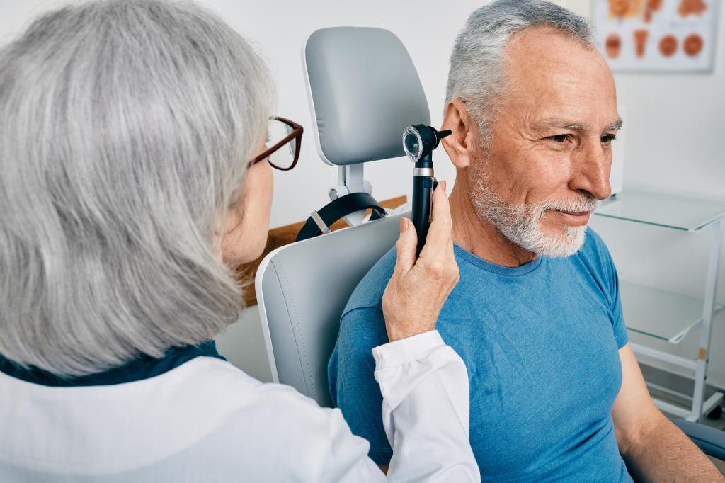 Tinnitus severity can be tough to assess. Here, a doctor examines a man's ears.
