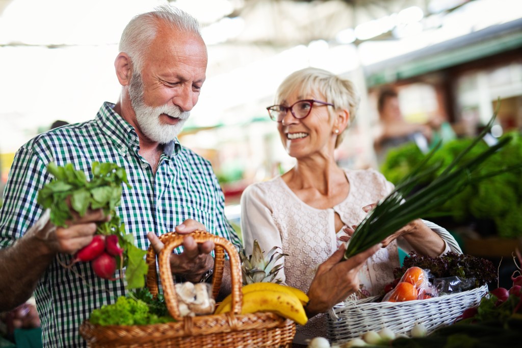 An elderly couple shops for produce. 