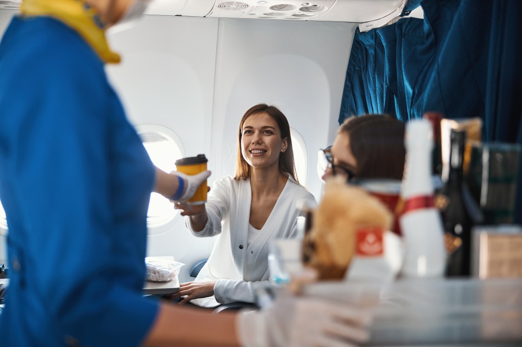 A woman getting coffee on a plane. 