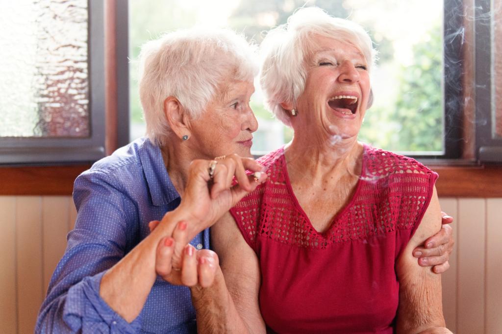 Two senior women smoke marijuana and laugh. 