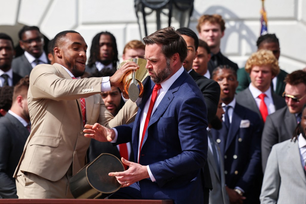 JD Vance drops the bottom half of the CFP trophy while TreVeyon Henderson manages to keep the top half from falling.
