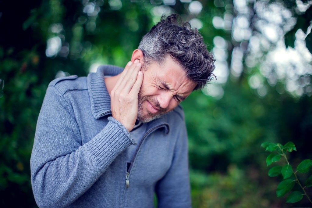 An estimated 50 million to 60 million Americans have experienced a ringing, buzzing or clicking in their ears that no one else hears, a frustrating condition known as tinnitus. Here, a man touches his ear in pain.