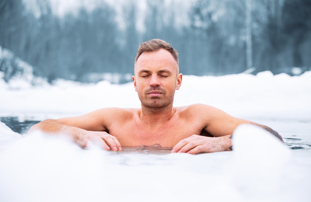 A man does a cold plunge in winter. 