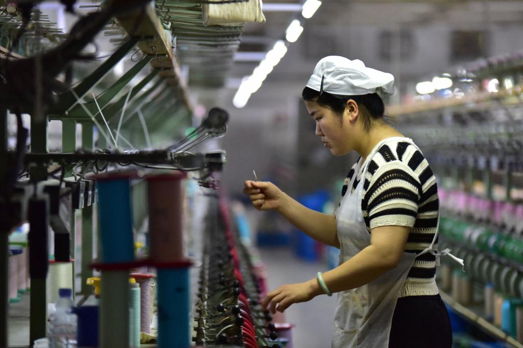 A worker checks a machine at a factory which produces silk cloth in Fuyang, in China's eastern Anhui province, on April 16, 2025. 