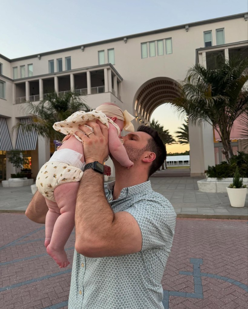 A man holding his baby daughter, who is aged 9 months, in front of a building