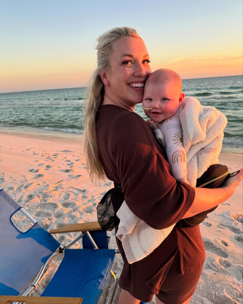A woman, Lauren Cummings Johnson, holding her baby, Lily Ann, on the beach