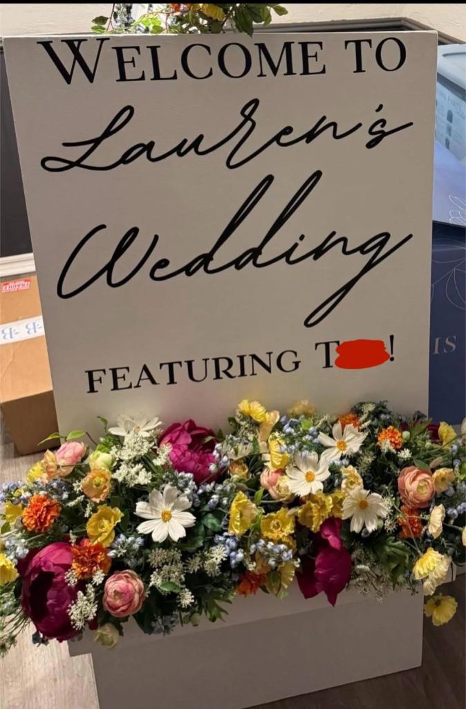 A sign with flowers on it, that went viral on Reddit for its controversial message from a bride